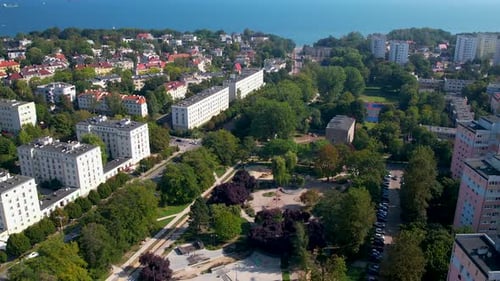 Vue aérienne en arrière d'un parc dans un quartier résidentiel de Gdynia pendant une journée ensoleillée avec la mer Baltique à l'arrière