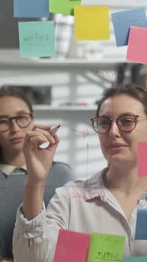 Team Brainstorming on Glass Whiteboard in Modern Office