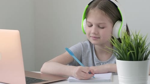 Schulmädchen trägt Kopfhörer während eines Online-Videoanrufs auf dem Laptop zu Hause