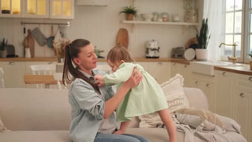 Mother and Baby Girl Playing on Couch