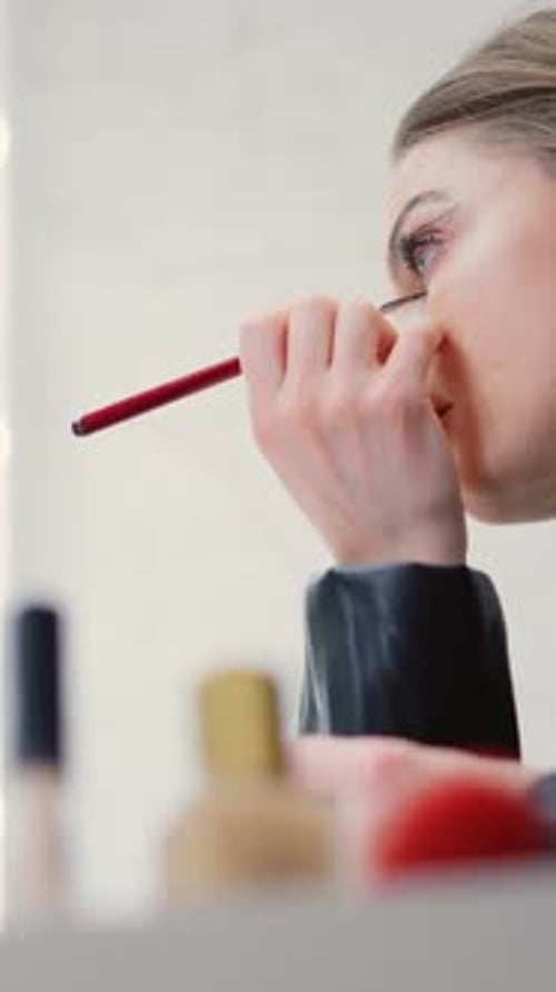 Woman Applying Makeup to Her Eye Line in a Backstage