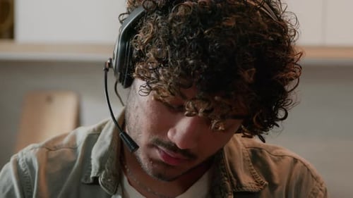 Young Adult Wearing Headset Writes in Notebook