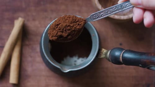 Pouring Ground Coffee Into Cezve with Teaspoon Close Up Top View