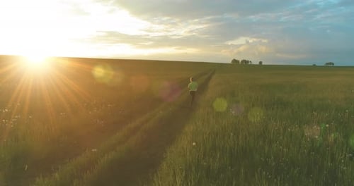 Sporty Child Runs Through a Green Wheat Field in Summer Rain