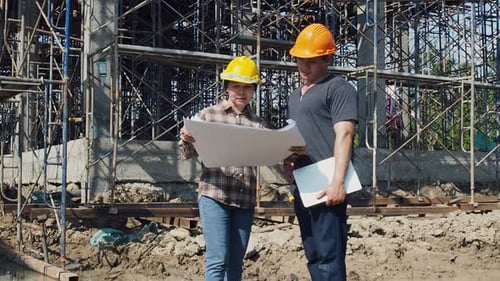 Construction manager and engineer discussing and checking plans on construction site.