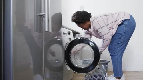 Woman Loading Clothes into Washing Machine at Home