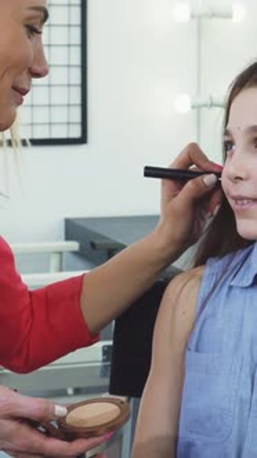 Joyful Little Girl Beams As Her Mom Applies Makeup with a Brush