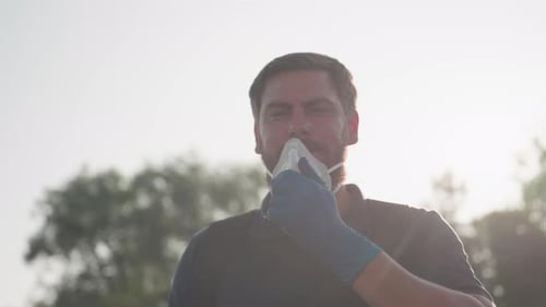 Man Outdoors Removing Face Mask, Bright Sunlight