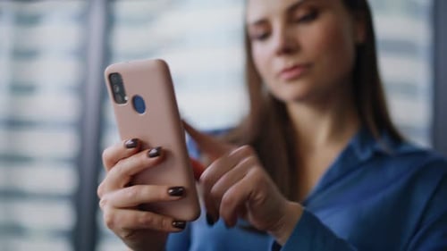 Elegant Brunette Tapping Cellphone Making Online Purchase in Office Closeup