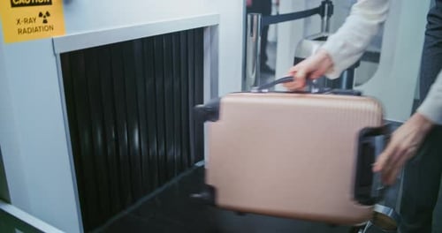 Security Checkpoint in Airport Terminal Passenger Places Suitcase on Conveyor Belt for Baggage