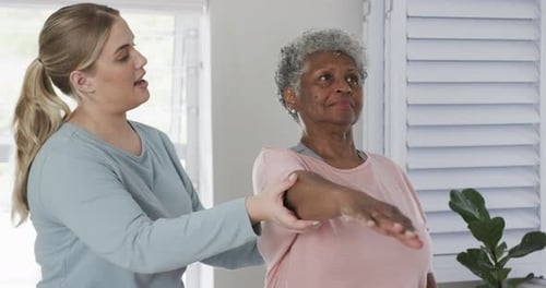 Caregiver Assists Senior Woman with Stretching Exercises