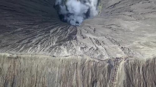 Steep ridge encircling smoking crater of Bromo volcano in Java, Indonesia - Aerial Fly-back wide sho