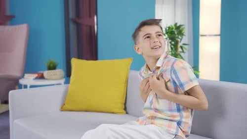 Young boy sitting in armchair is experiencing joy of success.