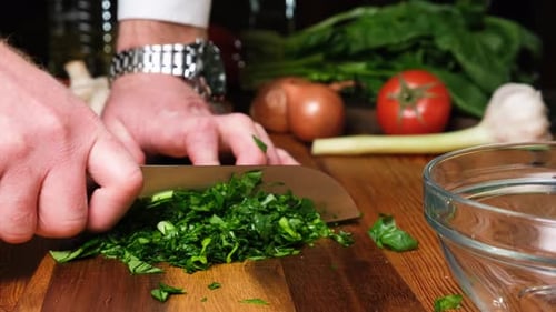 Person Chopping Herbs on Wooden Board