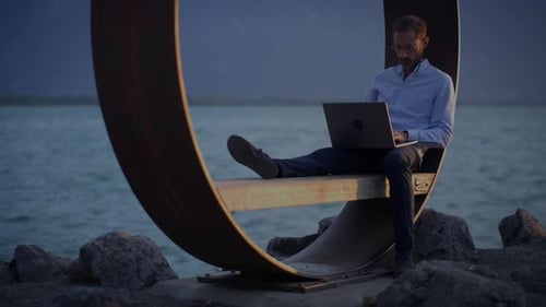 A Person Works on a Laptop Outdoors in a Creative Setting with Modern Design and a Sunset