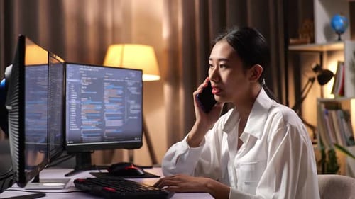 Une programmeuse asiatique parle sur un smartphone tout en créant une application de développement d'une Appli d'ingénieur logiciel