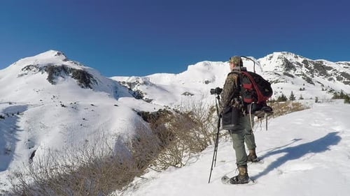 Hiker Photographs Snow-Covered Mountains on Sunny Winter Day