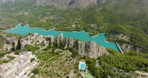 Mountain Valley Town Overlooking Turquoise Lake And Green Forest Aerial Drone Shot