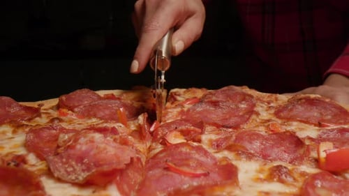 Hand Cuts Delicious Pizza with a Pizza Wheel