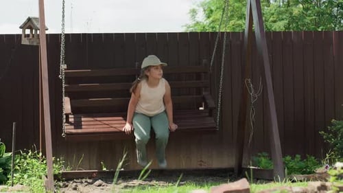Girl Relaxing on Wooden Swing in Suburban Backyard