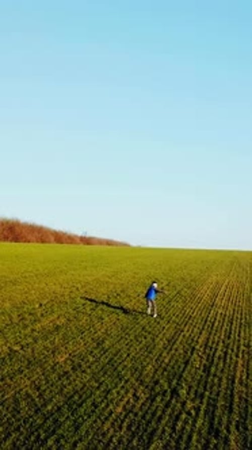 Cute boy is running around the green field in the early spring.