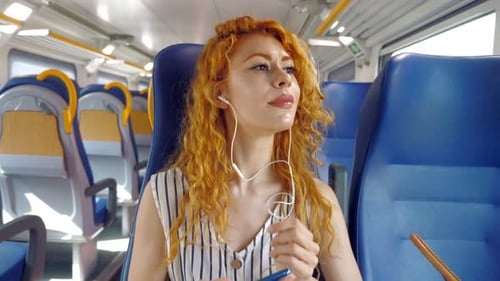 vacation, summer-woman on the train puts on headphones to listen to music