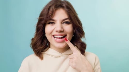 Woman Pointing To Her White Teeth Smiling