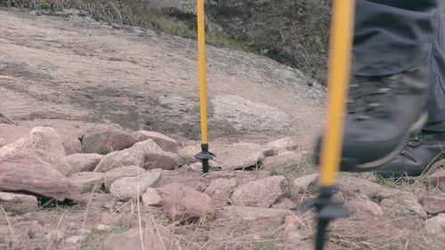 Hikers climbing a mountain path low angle. Boots of hikers on a rough terrain.