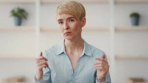Une femme fait des gestes expressifs alors qu'elle est engagée dans une conversation à l'intérieur