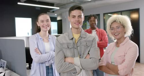 Smiling diverse team members standing with arms crossed in modern office