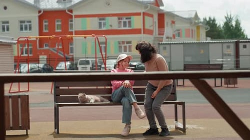 Woman and Girl Chatting on Bench with Cat
