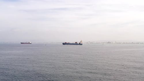Aerial footage of a container ship approaching a commercial port.