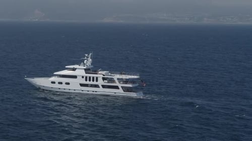 Aerial zoom out drone shot of yacht sailing in the deep blue sea. Luxury yacht cruising out at sea.