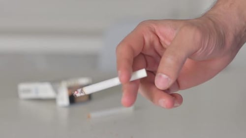 Gros plan de la main tenant une cigarette en fumant