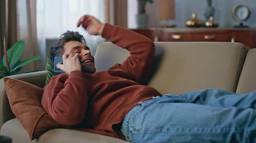 Chilling Guy Calling Smartphone Lying on Home Sofa Close Up Smiling Man Talking