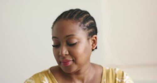 Mid-adult African American woman feeling smartphone vibration, checking health monitor on bed edge