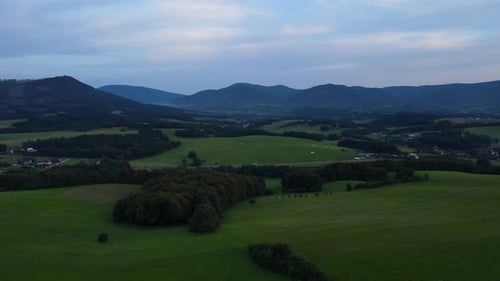Aerial view of a landscape full of hills during late afternoon and mountains in the background.