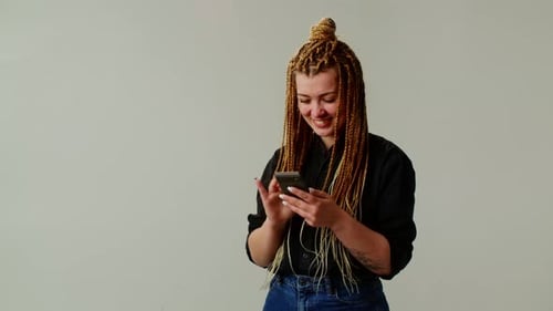 A Cheerful Attractive Girl with Pigtails Conducts a Cute Correspondence in a Smartphone
