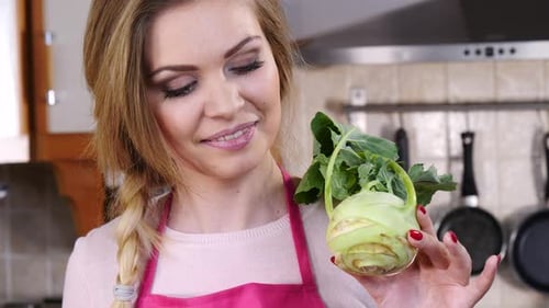 Woman Holding Fresh Kohlrabi in Kitchen