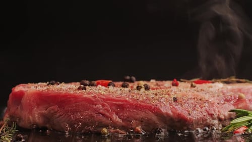 Fresh Marbled Beef with Pepper Salt and Rosemary Closeup Macro Cooking Juicy Steak on Grill with Oil