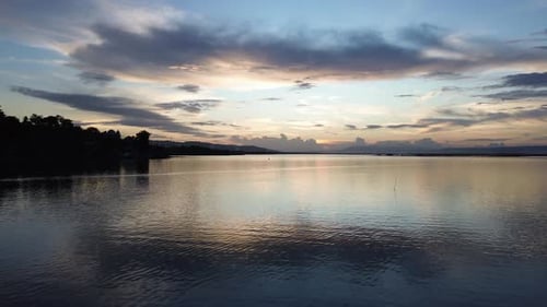 Aerial view over the water of the lake with sunset views and sun reflections