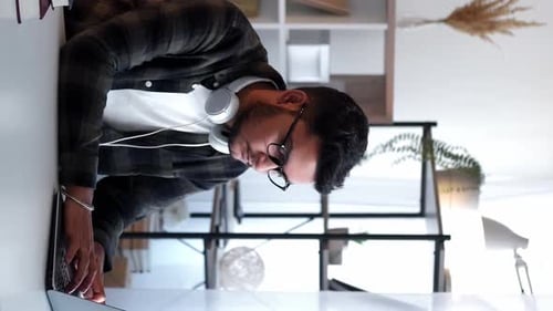 Young Adult Typing on Laptop at Desk Indoors