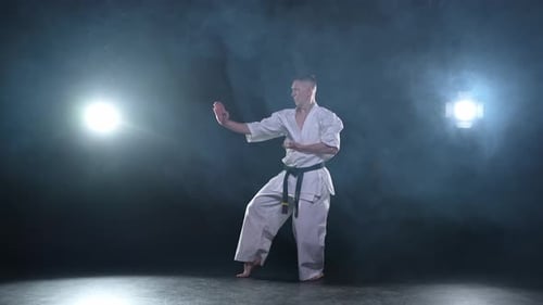 Starker Kämpfer im weißen Kimono für Karate-Kampfkünste mit schwarzem Gürtel bereitet sich auf den Kampf vor