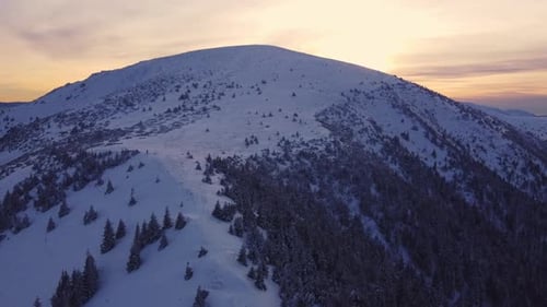 Flying Over a Snowy Mountain in Winter Nature at Sunset Aerial View From Above