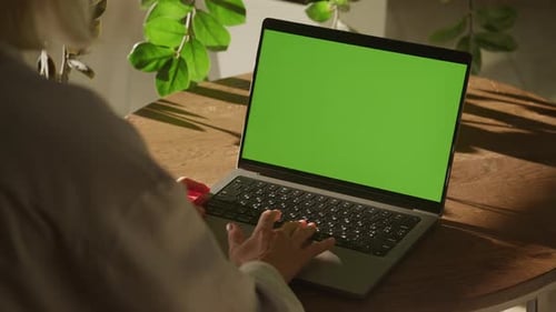 Handheld Shot of a Woman Single Scroll on a Laptop Computer with Green Screen Chroma Key Indoors
