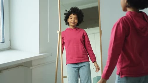 Liebe dich selbst Schöne junge lächelnde Afroamerikanerin tanzt und lockiges Haar berührt und genießt