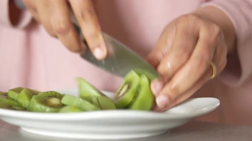 Frauen schneiden Kiwis von Hand mit Messer
