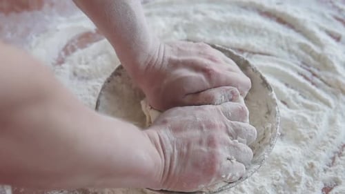 The cook kneads the dough from flour, eggs and water to make bread.