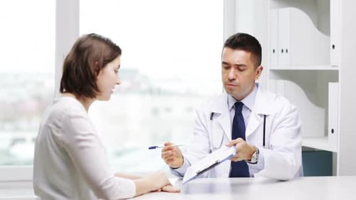 Woman talking with male doctor in clinic office