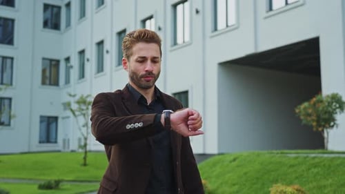 Man Checking Time While Waiting Outside a Modern Office in the Afternoon